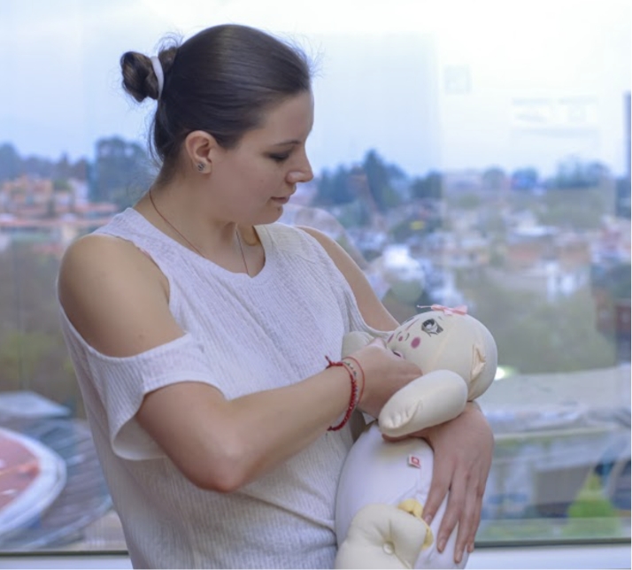 Mujer sosteniendo un muñeco de trapo como si fuese un bebé lactando