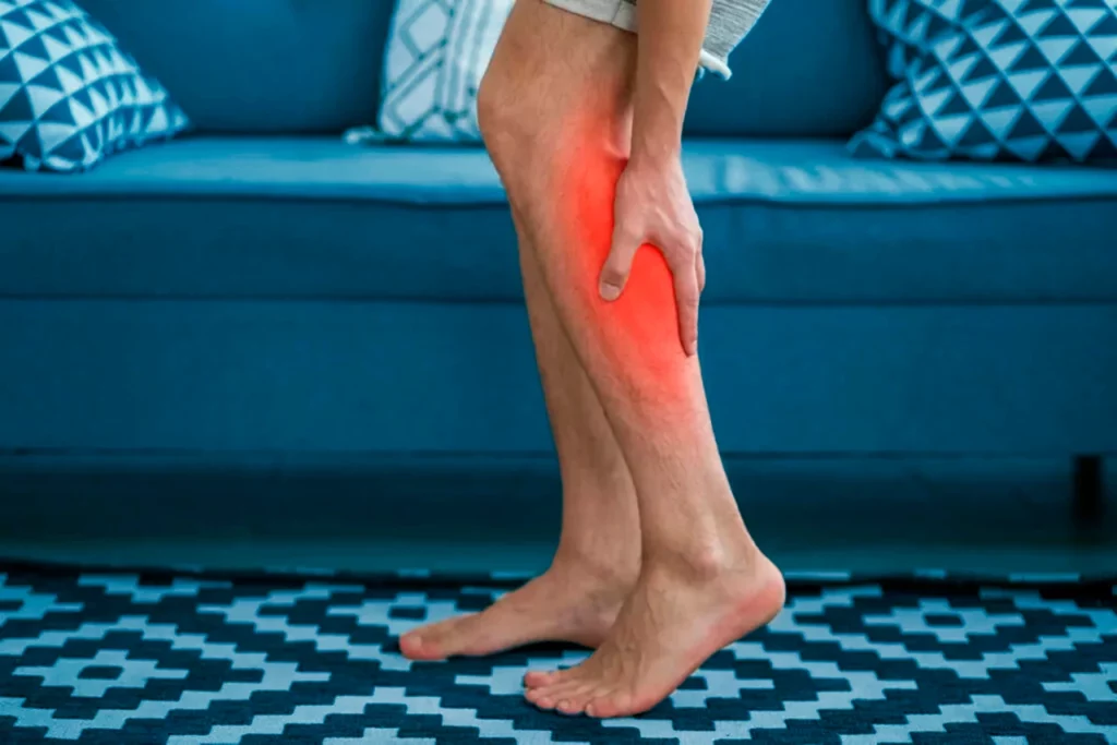 Hombre con enfermedad arterial periférica sobándose la pantorrilla debido al dolor que le genera esta condición.