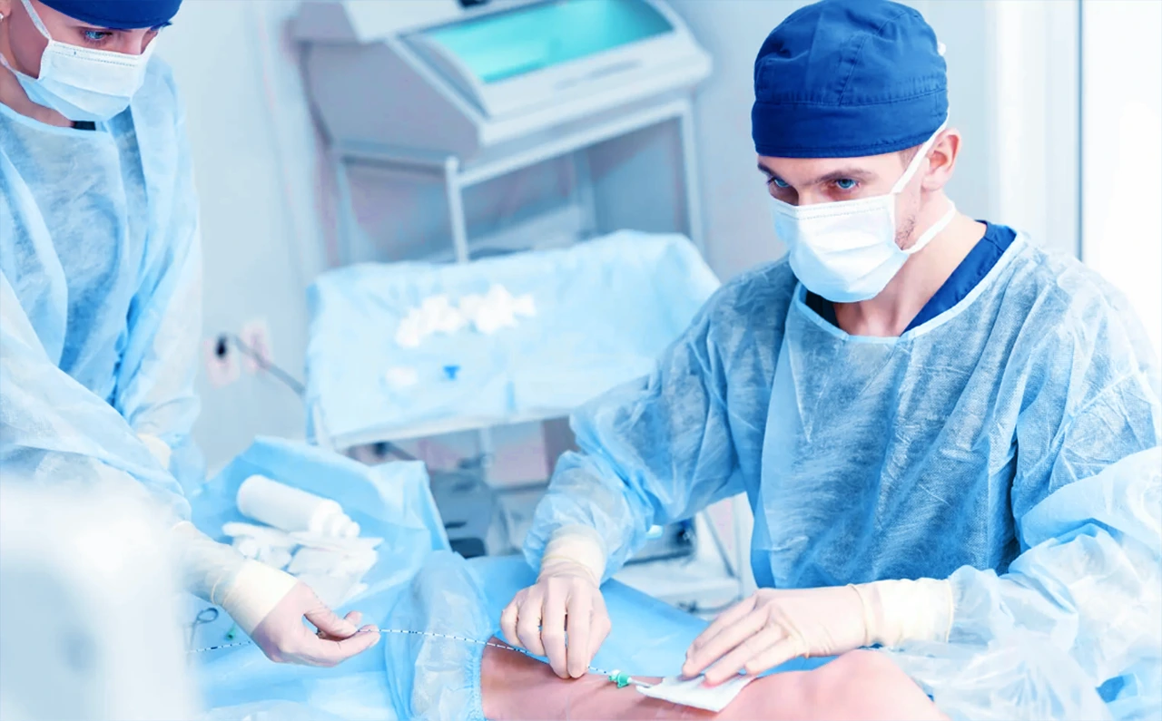 Médicos dando tratamiento a las várices de un paciente en un consultorio, mientras le realizan una safenectomía.