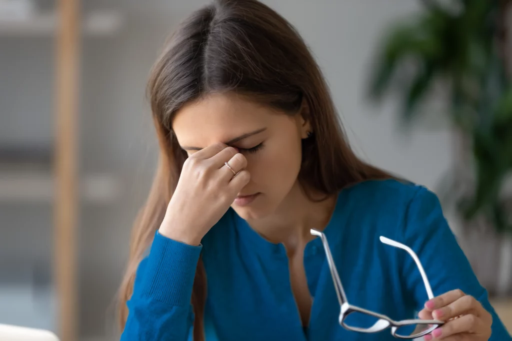 Mujer con lentes que está descansando la vista por el uso prolongado de dispositivos
