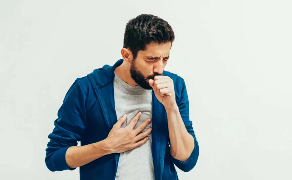 Hombre que presenta síntomas de influenza, de pie y tosiendo.