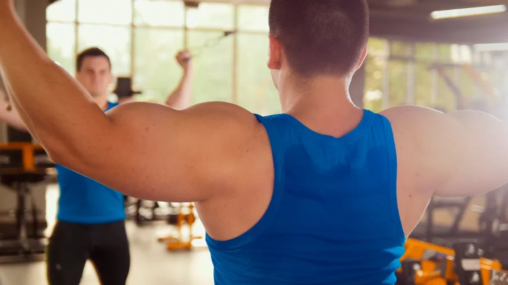 Hombre entrenando en el gimnasio antes de presentar lo que es un desgarro muscular por un mal movimiento. 