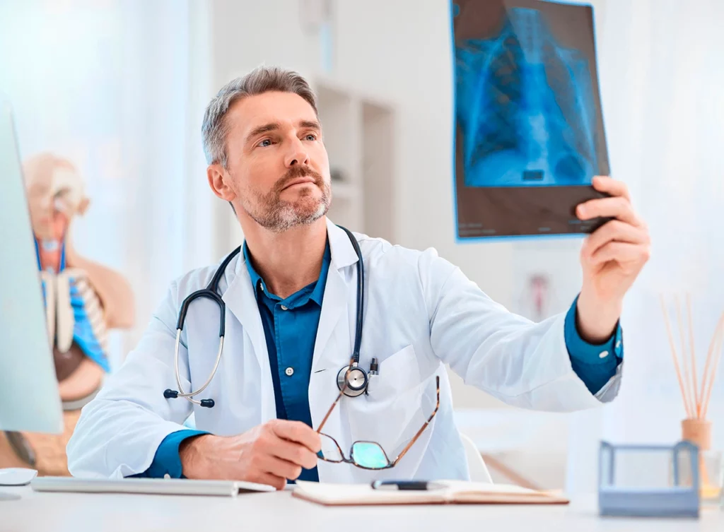 Médico revisando la radiografía de un paciente para identificar si presenta cardiomegalia.