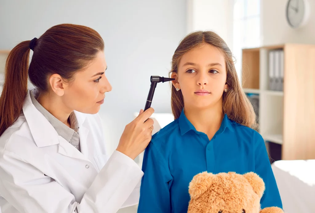  Otorrinolaringólogo pediatra revisando el interior de su paciente niña para ver si no está infectado.