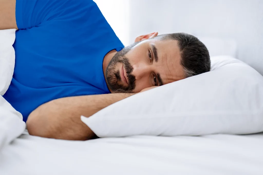 Imagen que representa el duermo, pero no descanso con un hombre despierto al amanecer, acostado sobre su almohada.
