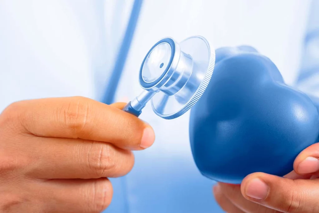 Médico con un estetoscopio sobre una figura de corazón, representando el análisis de los factores de riesgo cardiovascular que se pueden presentar.
