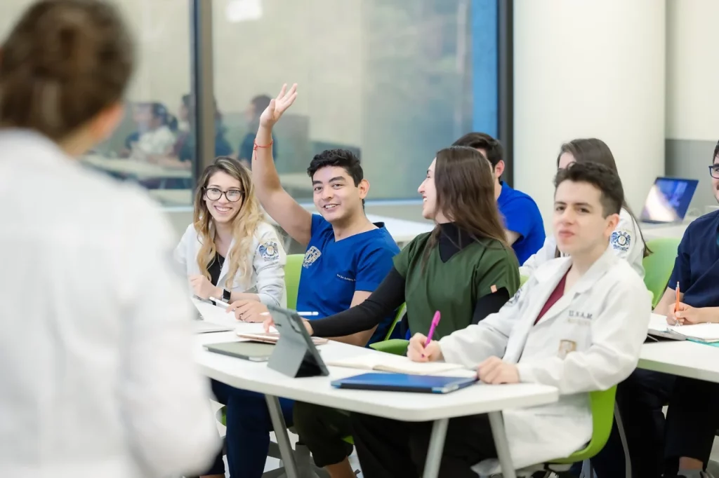 Alumnos de la residencia médica en charla, dentro de un aula, con un médico quien les hace preguntas sobre casos particulares.