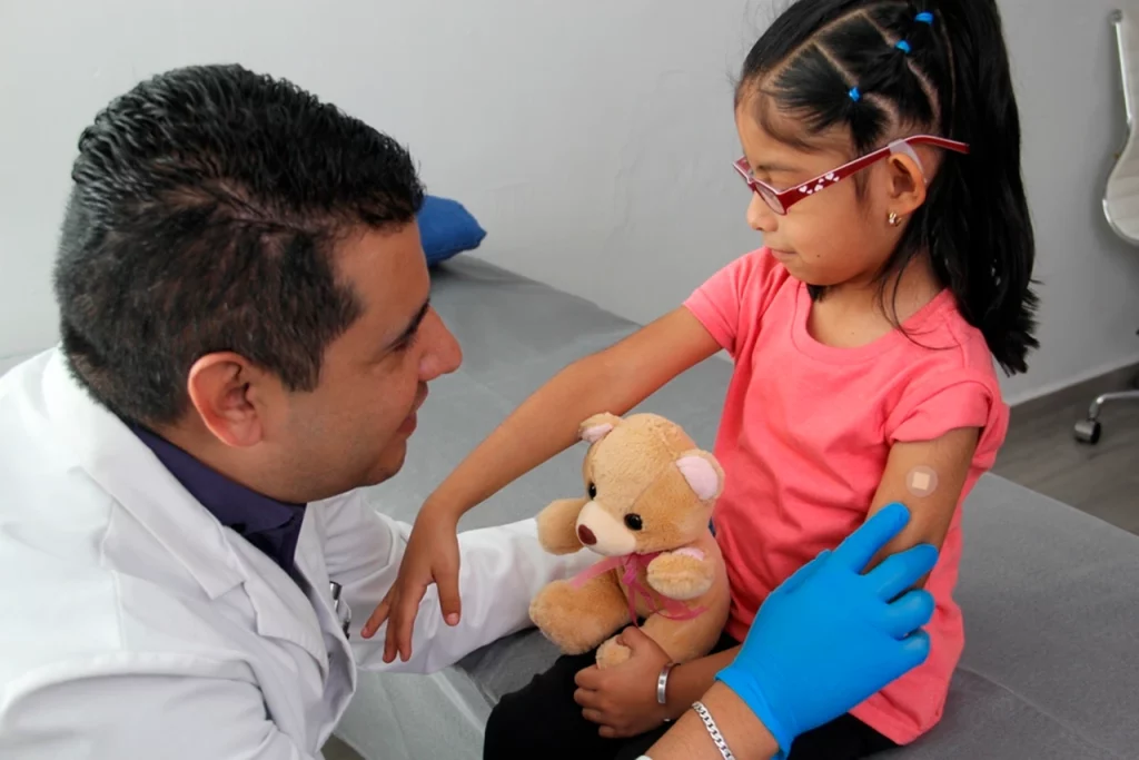 Niña en un consultorio, después de recibir una vacuna para lo que es el sarampión, con la vacuna triple viral.