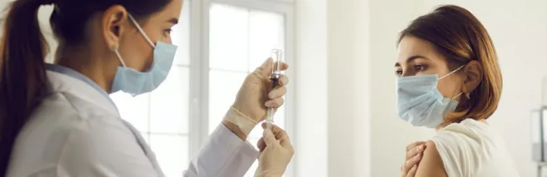 Médica preparando una vacuna para una paciente